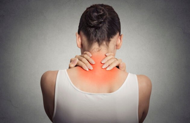 Healthy lifestyle. Back and spine disease. Closeup back view tired female massaging her neck colored in red isolated on gray background